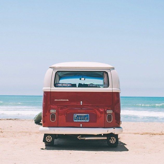 Mini van rouge avec le toit blanc  sur la plage au bord de la mer