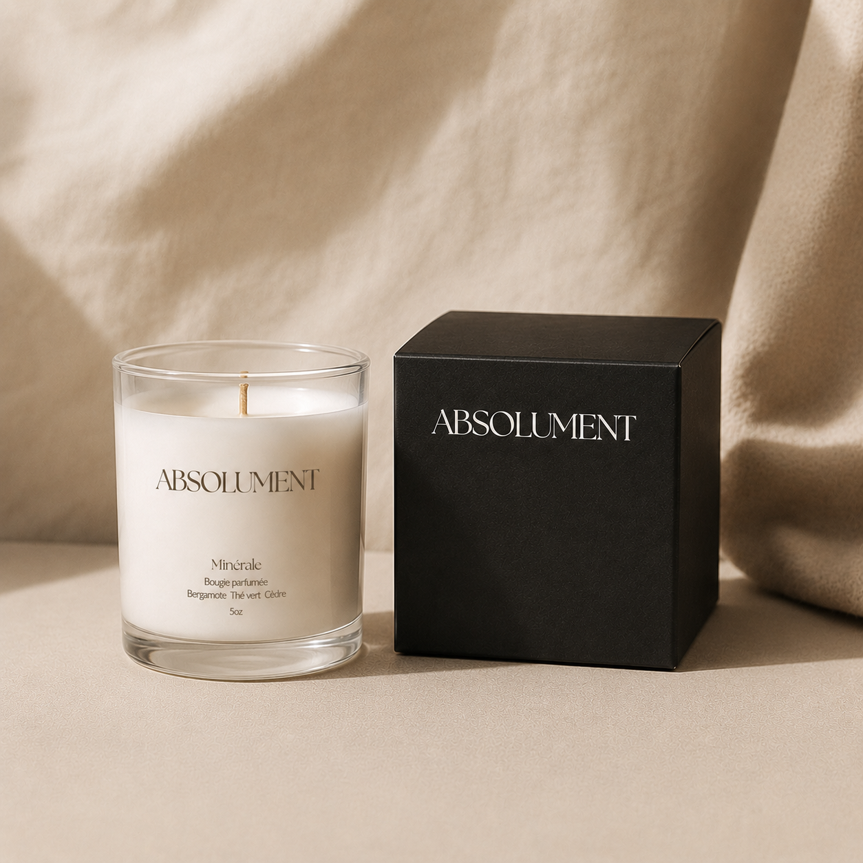 Bougie parfumée Minérale d'Absolument aux notes de bergamote, thé vert et cèdre présentée à côté d'une boîte noire avec logo Absolument en blanc.